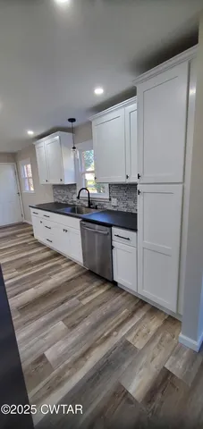 a large kitchen with granite countertop a sink and cabinets