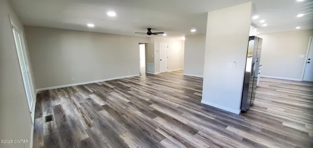 an empty room with wooden floor and a hallway