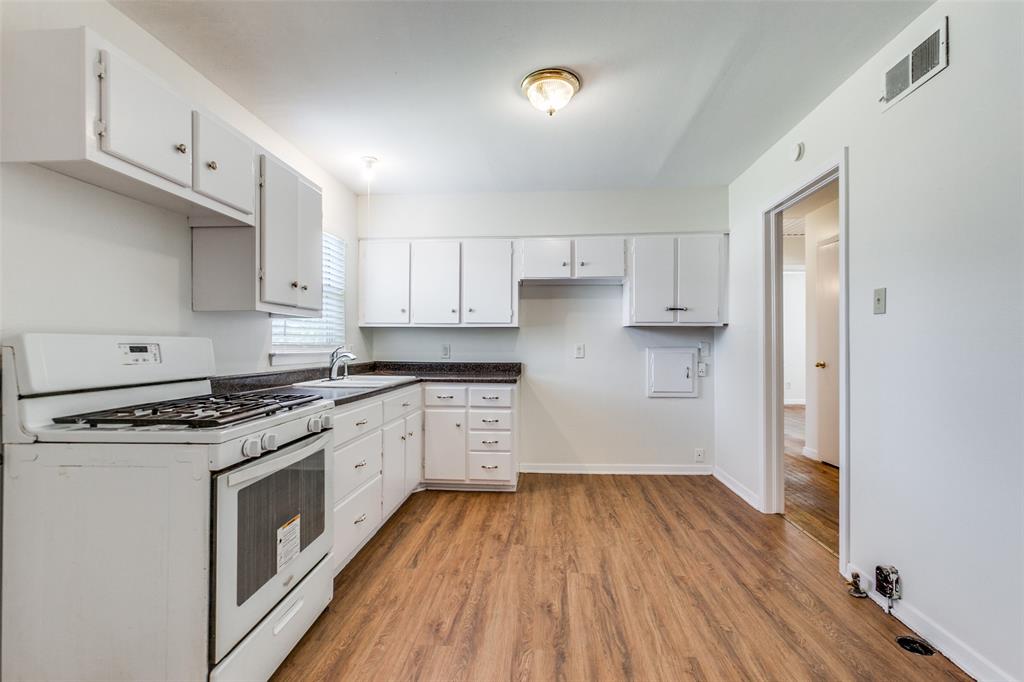 10815 Ruth Ann Drive Dallas, TX 75228 - Photo 6 of 12 a kitchen with a hard wood floor white cabinets and stainless steel appliances