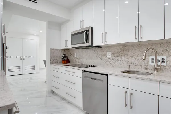 a kitchen with granite countertop white cabinets and stainless steel appliances