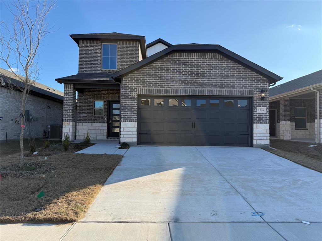 View of front facade featuring brick siding, driveway, and an attached garage