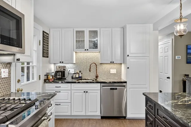 a kitchen with stainless steel appliances granite countertop a sink stove oven and white cabinets with wooden floor