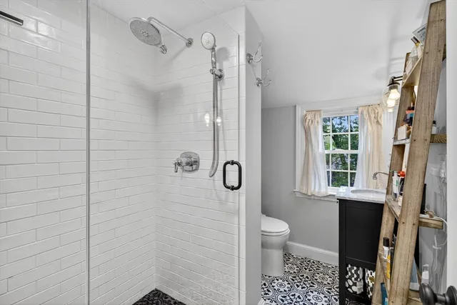 a bathroom with a granite countertop shower a toilet and a window