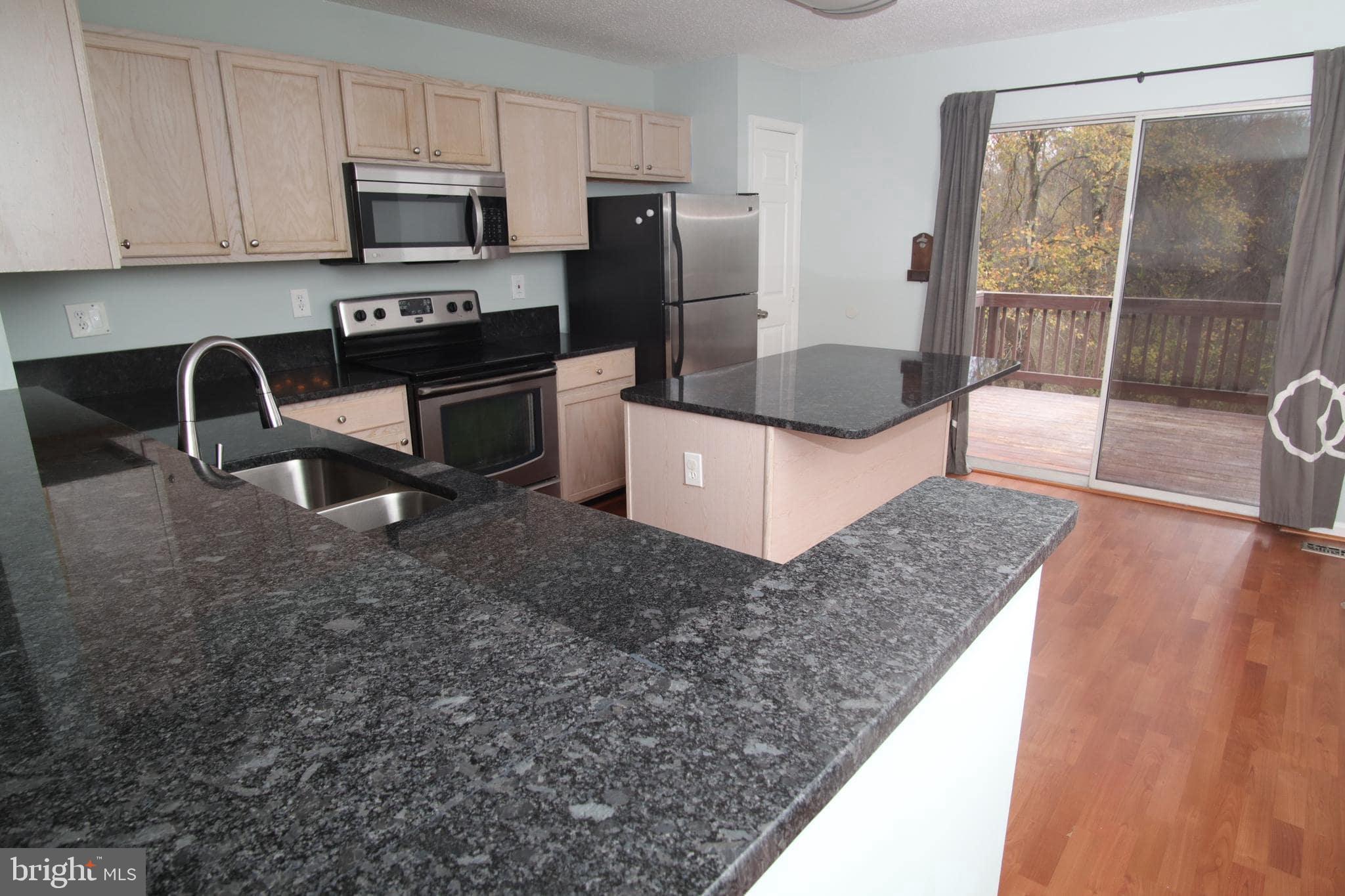 a kitchen with stainless steel appliances granite countertop a refrigerator a stove a sink a counter space and cabinets