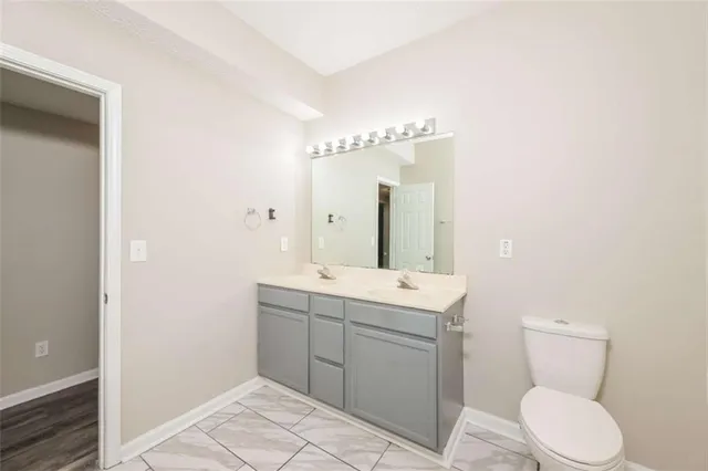 a bathroom with a double vanity sink a toilet and shower