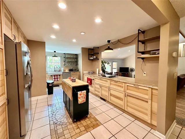 a large kitchen with stainless steel appliances kitchen island granite countertop a refrigerator and a stove