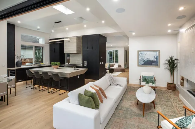 a living room with lots of furniture kitchen view and a large mirror