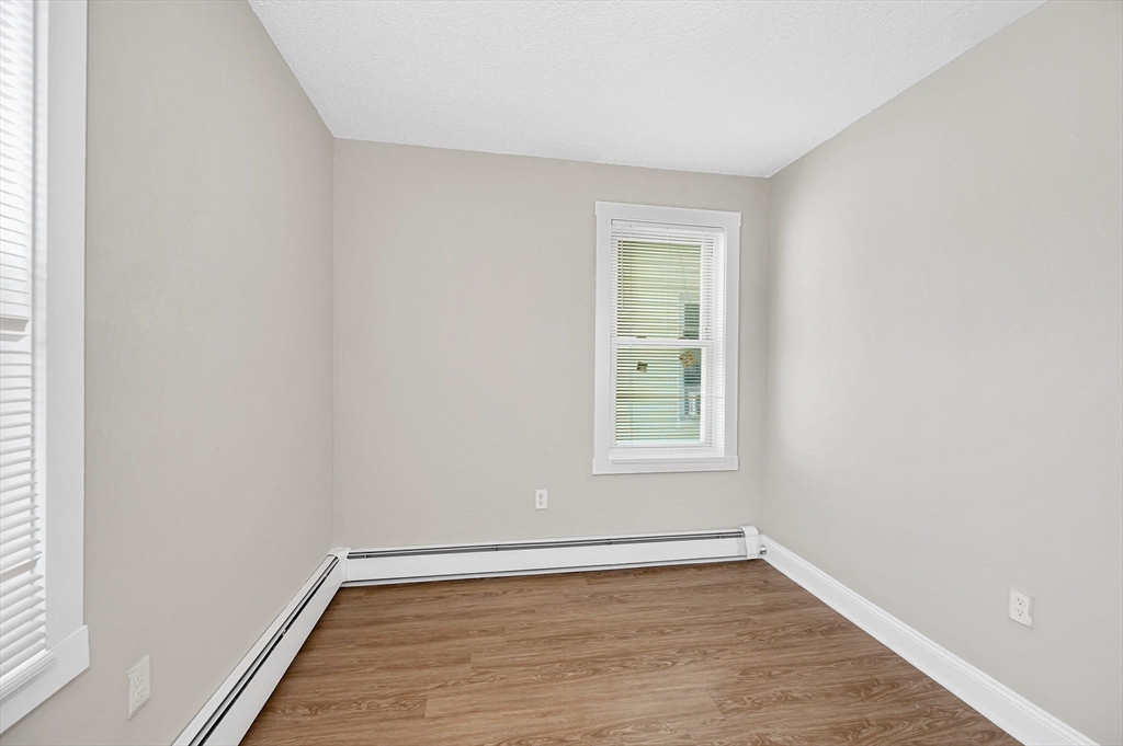 50 1/2 Common Street, Unit 5 Lawrence, MA 01840 - Photo 15 of 18 an empty room with wooden floor and windows