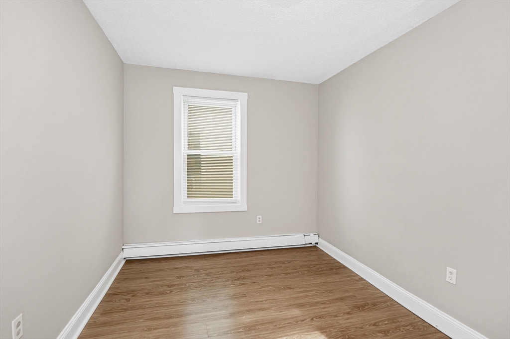 50 1/2 Common Street, Unit 5 Lawrence, MA 01840 - Photo 17 of 18 an empty room with wooden floor and windows