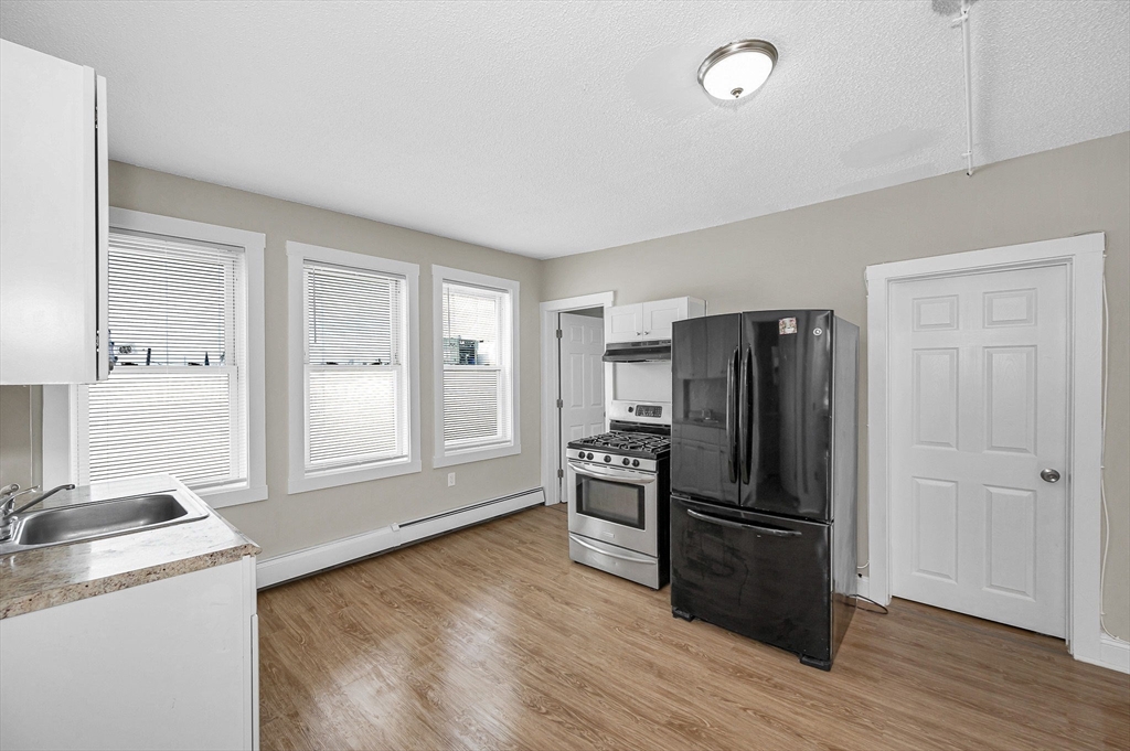 50 1/2 Common Street, Unit 5 Lawrence, MA 01840 - Photo 6 of 18 a kitchen with granite countertop a refrigerator and a stove top oven