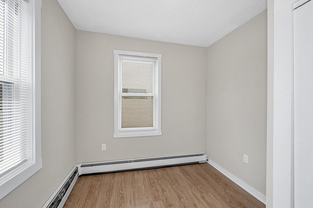 50 1/2 Common Street, Unit 5 Lawrence, MA 01840 - Photo 10 of 18 an empty room with wooden floor and windows