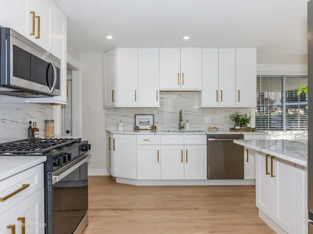 a kitchen with stainless steel appliances granite countertop a stove a sink and a microwave