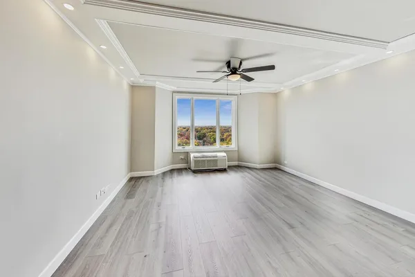 a view of a room with wooden floor ceiling fan and window