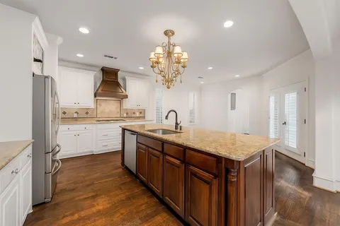 a kitchen with kitchen island granite countertop a sink refrigerator and cabinets