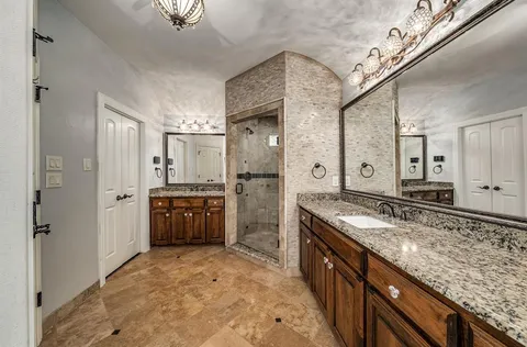 a large bathroom with a granite countertop double vanity sink a mirror and a shower