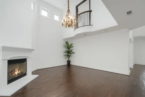 a view of an empty room with chandelier and fireplace