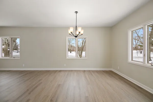 a view of a room with wooden floor chandelier and windows