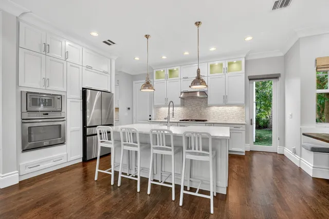 a kitchen with stainless steel appliances white cabinets and a wooden floors