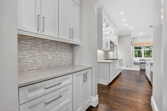 a bathroom with a granite countertop toilet a sink a mirror and a window