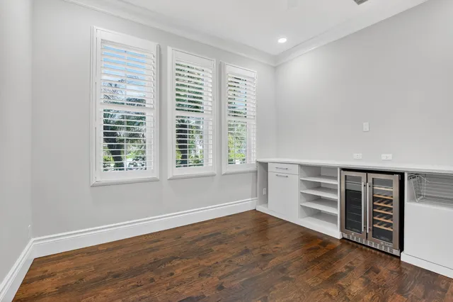 an empty room with wooden floor cabinet and windows
