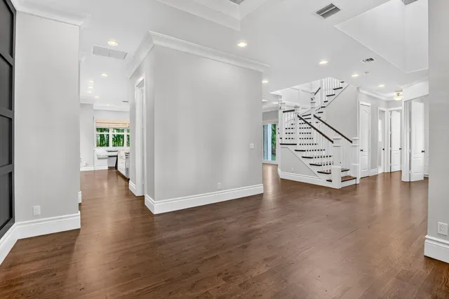 a view of an empty room with wooden floor and stairs