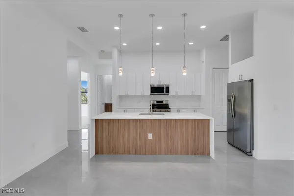 a view of kitchen with stainless steel appliances granite countertop refrigerator and a sink