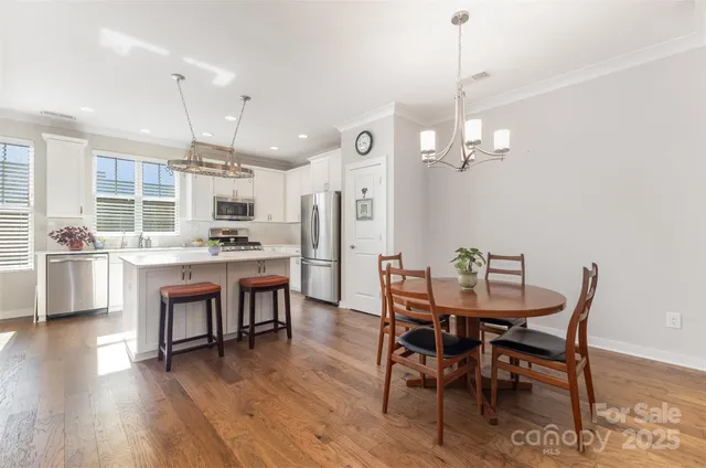 a view of a dining room and livingroom with furniture wooden floor a chandelier