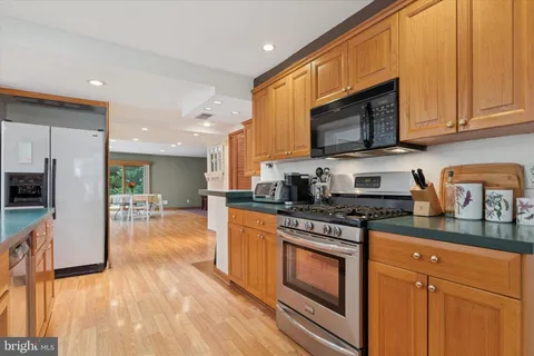 a kitchen with stainless steel appliances granite countertop a stove a sink dishwasher and a microwave oven with wooden cabinets