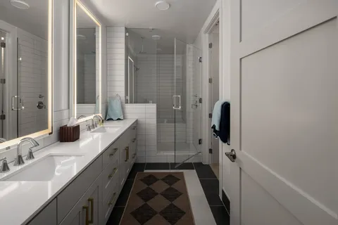 a bathroom with a double vanity sink a mirror and shower