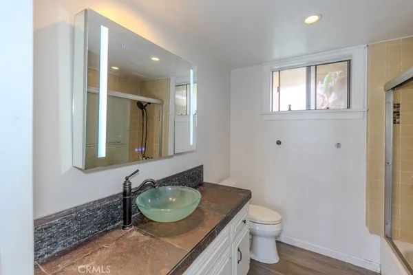 a bathroom with a granite countertop toilet a sink and a mirror