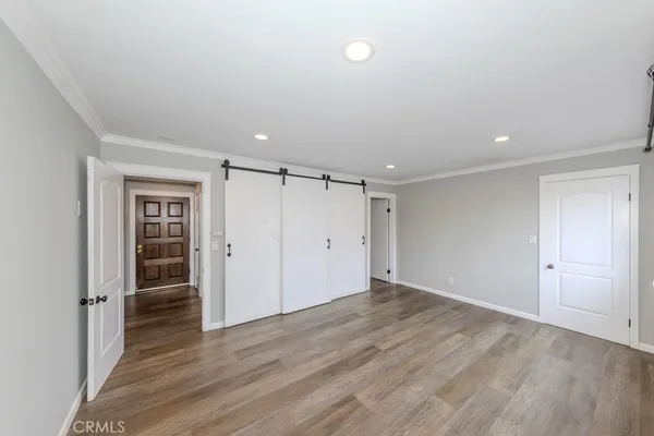 a view of an empty room with wooden floor and closet