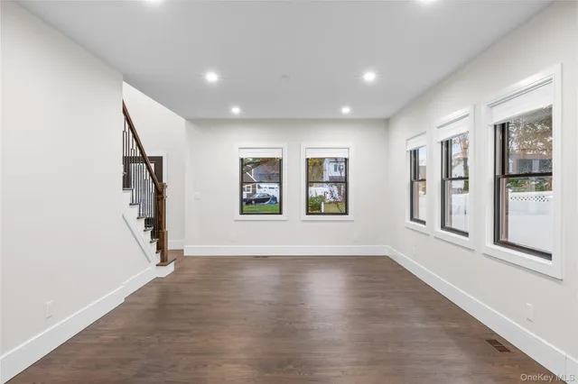a view of an empty room with wooden floor and a ceiling fan