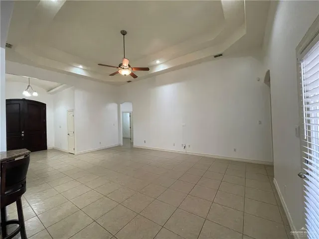 an empty room with chandelier fan and windows