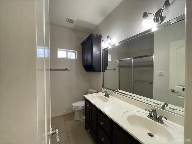 a bathroom with a double vanity sink toilet and mirror