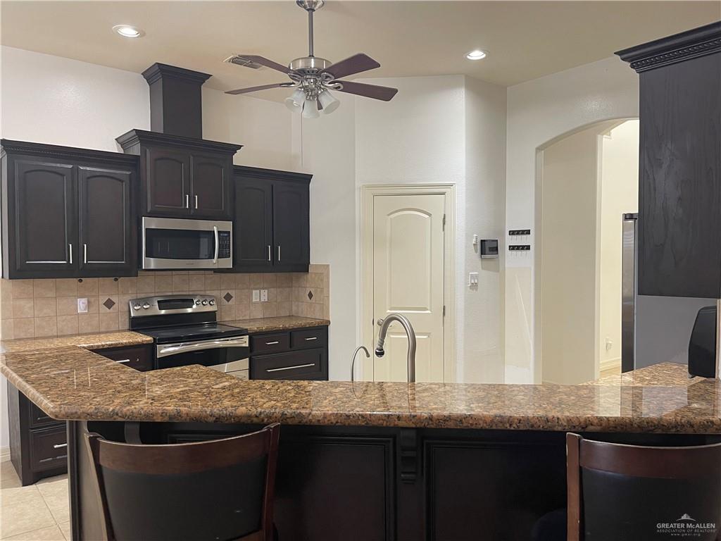 1000 South Flag Street Pharr, TX 78577 - Photo 22 of 24 a kitchen with granite countertop stainless steel appliances a sink stove top oven and refrigerator
