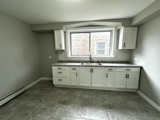 a room with cabinets appliances a sink and a window