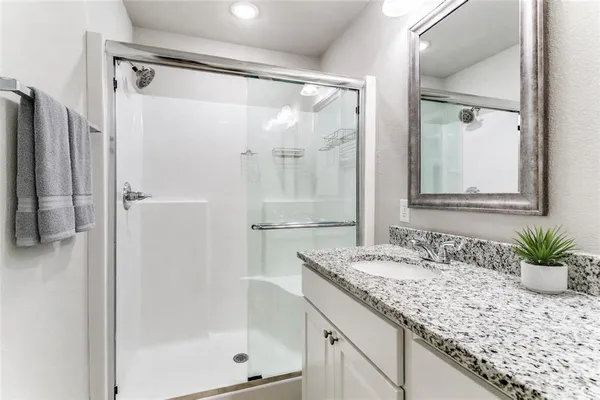 a bathroom with a granite countertop sink a mirror and a shower