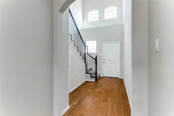 a view of a hallway to a bedroom with wooden floor and stairs