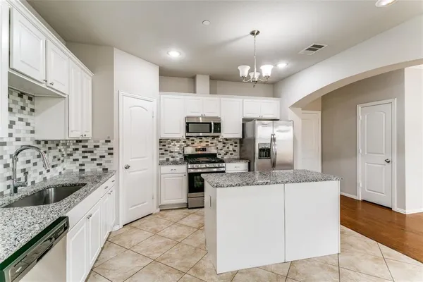 a kitchen with kitchen island granite countertop a sink stove and refrigerator