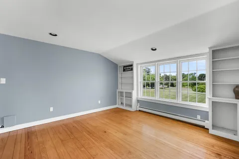a view of an empty room with a window and wooden floor