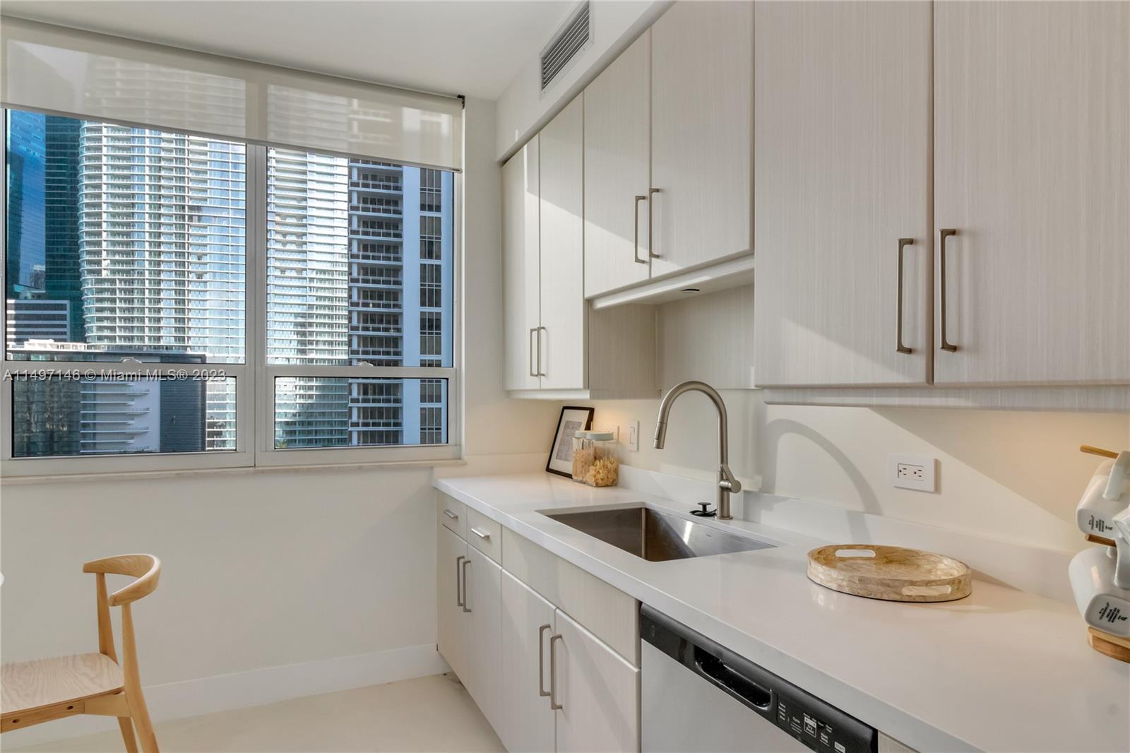 801 Brickell Key Boulevard, Unit 1102 Miami, FL 33131 - Photo 13 of 15 a kitchen with stainless steel appliances granite countertop a sink and a wooden cabinets