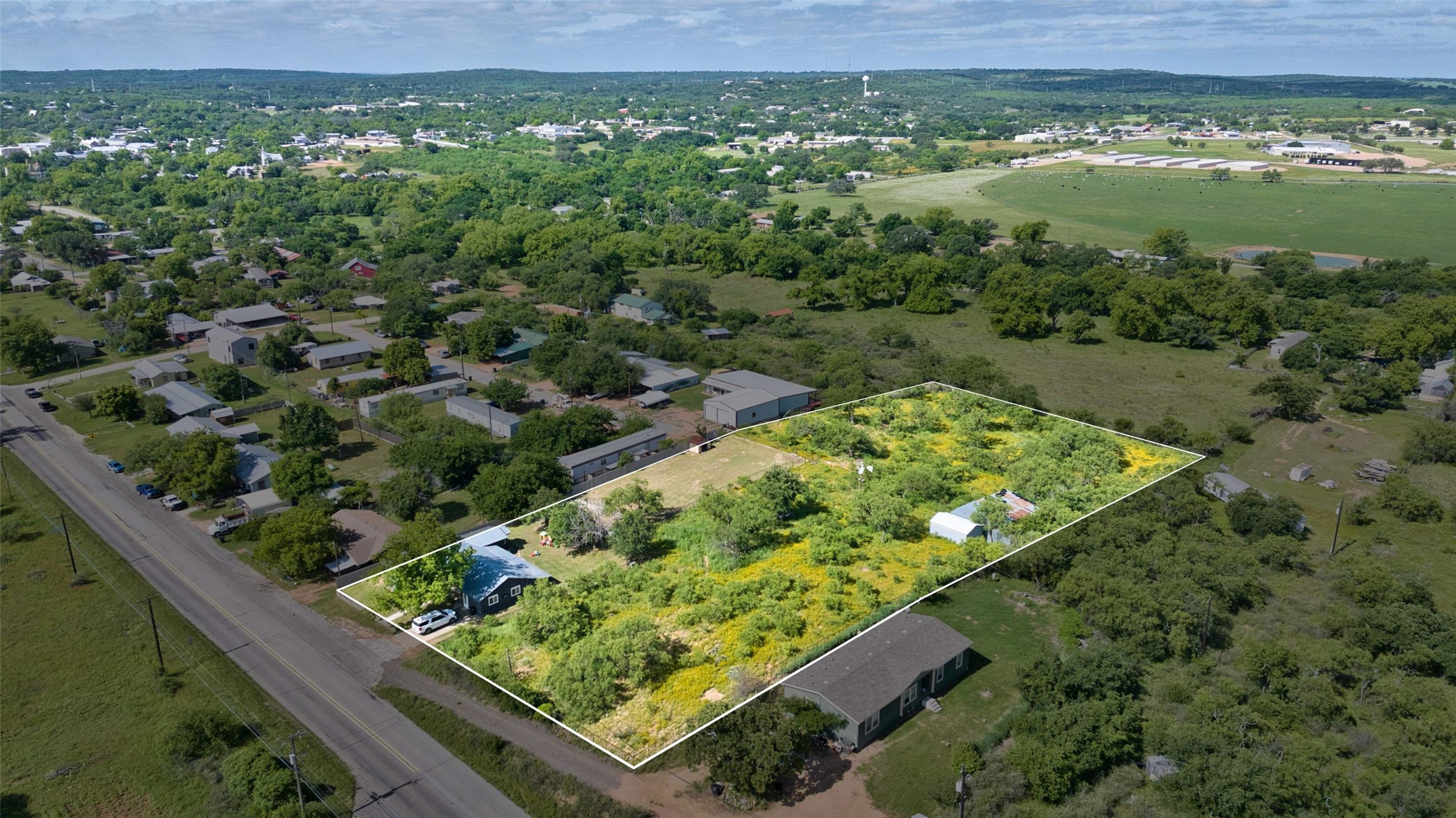 904 Bluebonnet Road Mason, TX 76856 - Photo 6 of 28 Expansive property outlined with white markers, featuring a mix of mature trees and open land with visible yellow wildflowers