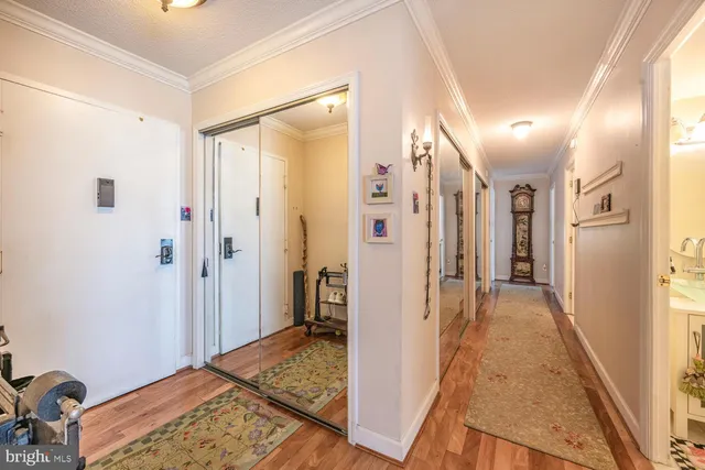a view of a hallway with wooden floor and a bathroom