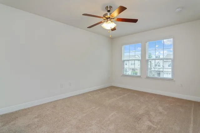 an empty room with windows and fan