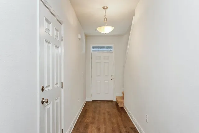 a view of a hallway with wooden floor and a bathroom