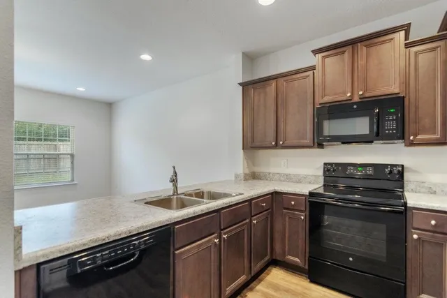 a kitchen with granite countertop a sink stove and microwave