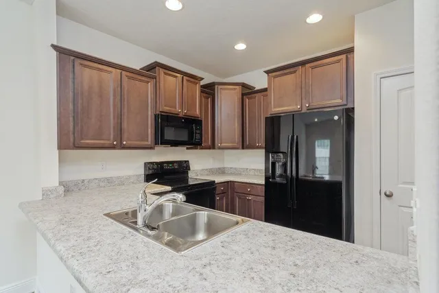 a kitchen with granite countertop a refrigerator stove and sink