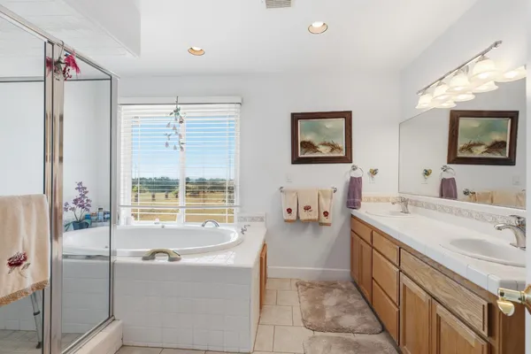a spacious bathroom with a tub a sink and mirror