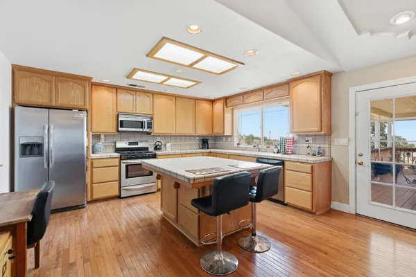 a kitchen with stainless steel appliances granite countertop a stove a sink dishwasher a refrigerator and a dining table with wooden floor