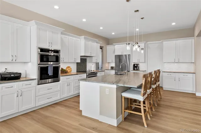 a kitchen with stainless steel appliances kitchen island granite countertop a dining table chairs and granite counter tops